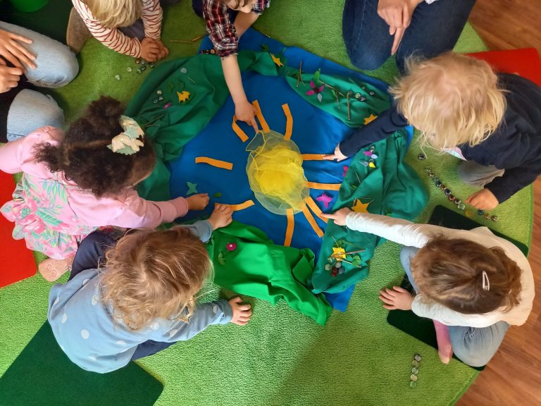 Kinder legen mit verschiedenen Materialien ein Frühlingsbild