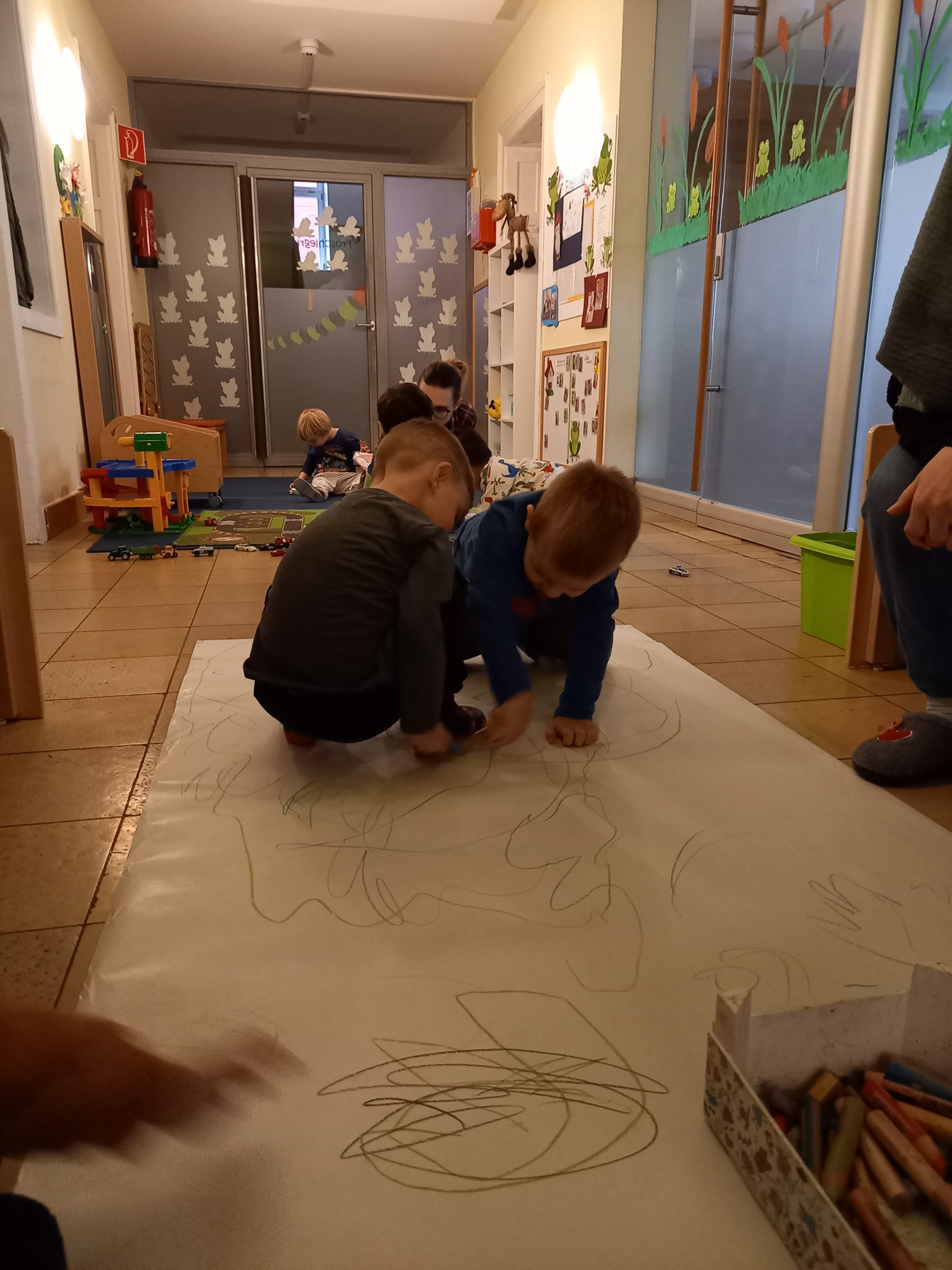 Kinder malen auf einem großen Papier am Boden