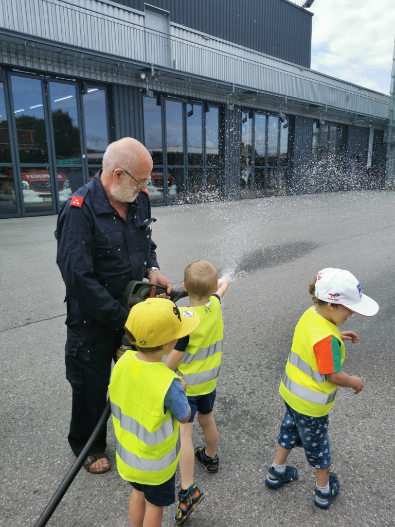 Kinder und Feuerwehrmann spritzen Wasser